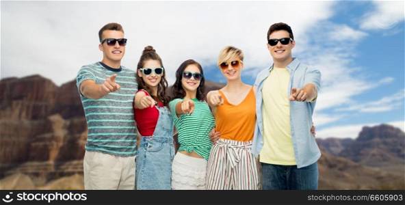 travel, tourism and summer holidays concept - group of happy smiling friends in sunglasses pointing at you over grand canyon national park background. friends pointing at you over grand canyon