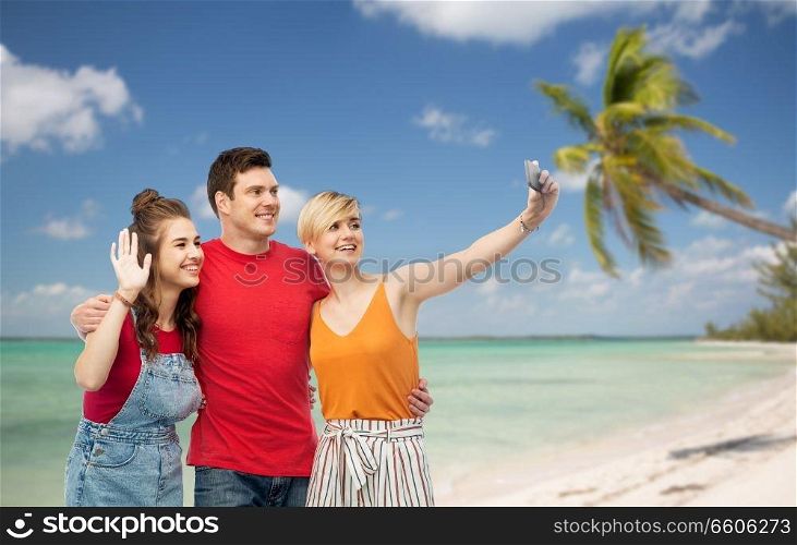 travel, tourism and summer holidays concept - group of happy smiling friends taking selfie by smartphone and hugging over exotic tropical beach with palm trees background. friends taking selfie by smartphone and hugging