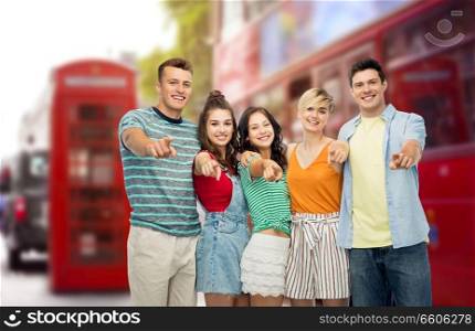 travel, tourism and summer holidays concept - group of happy smiling friends hugging pointing at you over london city street background. friends pointing at you over london city street