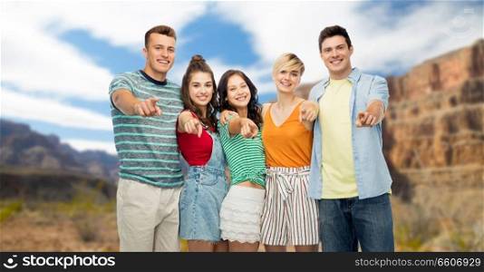 travel, tourism and summer holidays concept - group of happy smiling friends hugging pointing at you over grand canyon national park background. friends pointing at you over grand canyon
