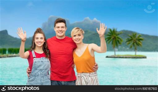 travel, tourism and summer holidays concept - group of happy smiling friends hugging at touristic resort over bora bora island beach background. happy friends hugging over bora bora beach