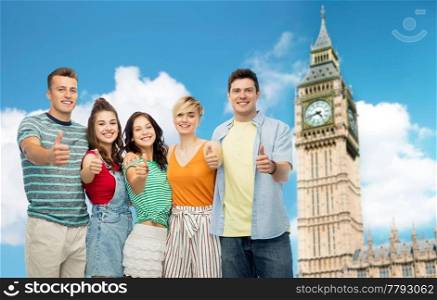 travel, tourism and summer holidays concept - group of happy smiling friends hugging showing thumbs up over clock tower in london background. friends showing thumbs up over tower in london