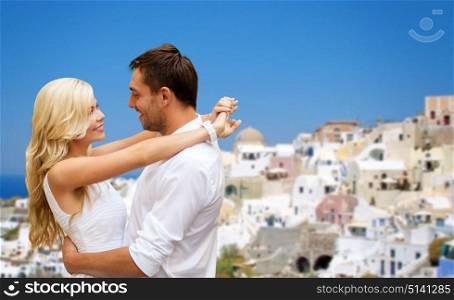 travel, tourism and summer holidays concept - happy couple hugging over santorini island background. happy couple hugging over santorini island