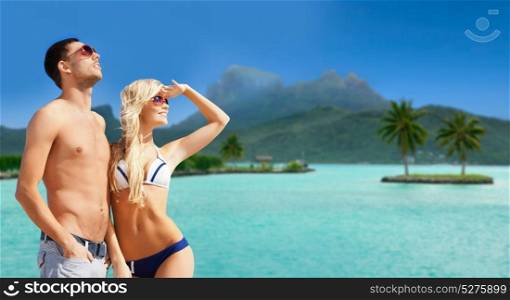 travel, tourism and summer holidays concept - happy couple in sunglasses at touristic resort over exotic bora bora island beach background. happy couple on over bora bora island beach