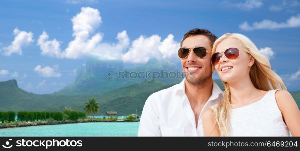 travel, tourism and summer holidays concept - happy couple in sunglasses at touristic resort over exotic bora bora island background. happy couple on over bora bora background