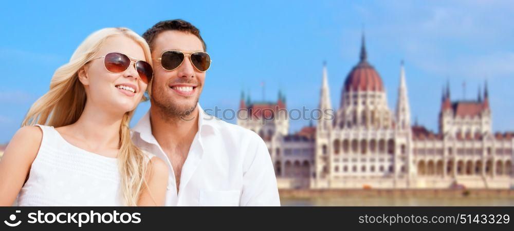 travel, tourism and summer holidays concept - happy couple over house of parliament in budapest background. happy couple over house of parliament in budapest