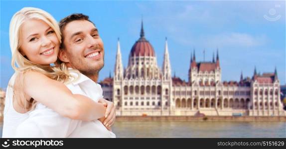 travel, tourism and summer holidays concept - happy couple over house of parliament in budapest background. happy couple over house of parliament in budapest