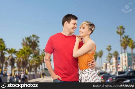 travel, tourism and summer holidays concept - happy smiling couple hugging over venice beach background in california. happy couple hugging