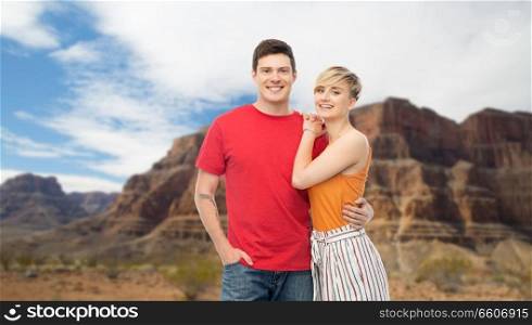 travel, tourism and summer holidays concept - happy smiling couple hugging over grand canyon national park background. happy couple hugging