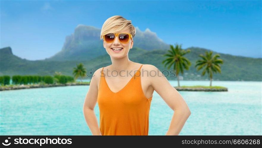 travel, tourism and summer holidays concept - happy smiling teenage girl in sunglasses at touristic resort over bora bora island beach background. happy smiling teenage girl over bora bora beach