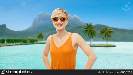 travel, tourism and summer holidays concept - happy smiling teenage girl in sunglasses at touristic resort over bora bora island beach background. happy smiling teenage girl over bora bora beach