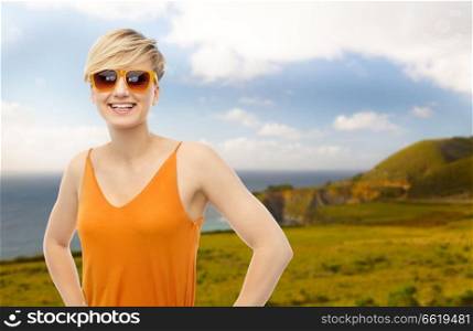 travel, tourism and summer holidays concept - happy smiling teenage girl in sunglasses over big sur coast of california background. happy smiling teenage girl over background