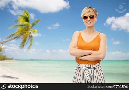 travel, tourism and summer holidays concept - happy smiling young woman in sunglasses over exotic tropical beach with palm trees background. happy smiling young woman over white background