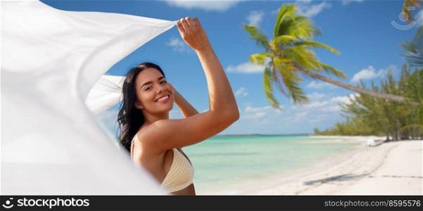 travel, tourism and summer holidays concept - happy smiling young woman in bikini swimsuit with cover-up over tropical beach background in french polynesia. woman in bikini swimsuit with cover-up on beach