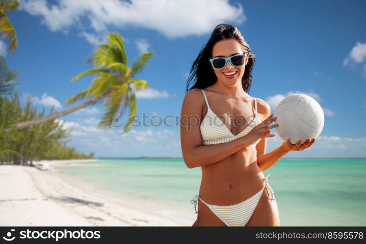 travel, tourism and summer holidays concept - happy smiling young woman in bikini swimsuit posing with volleyball over tropical beach background in french polynesia. woman in bikini posing with volleyball on beach