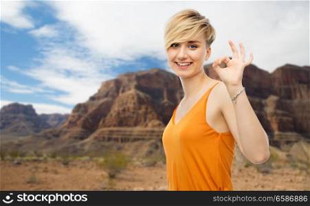 travel, tourism and summer holidays concept - happy smiling young woman showing ok hand sign over grand canyon national park background. happy smiling young woman showing ok hand sign