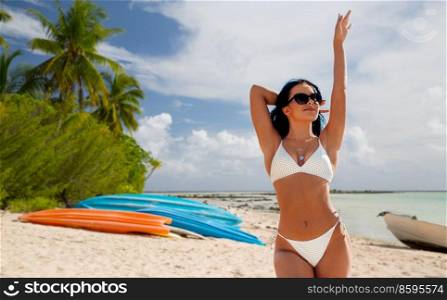 travel, tourism and summer holidays concept - happy young woman in bikini swimsuit over tropical beach background in french polynesia. happy young woman in bikini swimsuit on beach