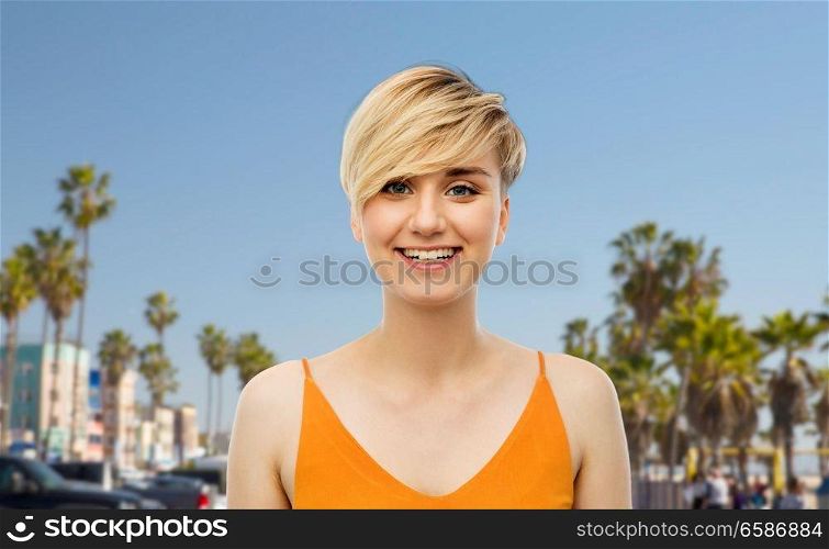 travel, tourism and summer holidays concept - portrait of happy smiling young woman over venice beach background in california. portrait of happy smiling young woman
