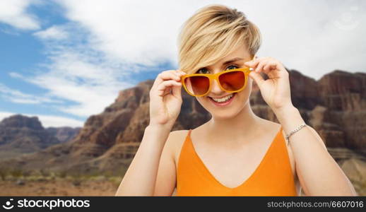 travel, tourism and summer holidays concept - portrait of happy smiling young woman in sunglasses over grand canyon national park background. portrait of smiling young woman in sunglasses