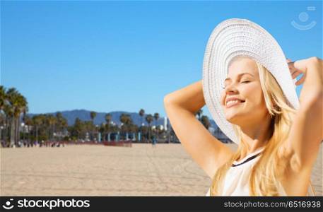 travel, tourism and summer vacation concept - beautiful woman in hat enjoying sun over venice beach background in california. beautiful woman enjoying summer over venice beach. beautiful woman enjoying summer over venice beach
