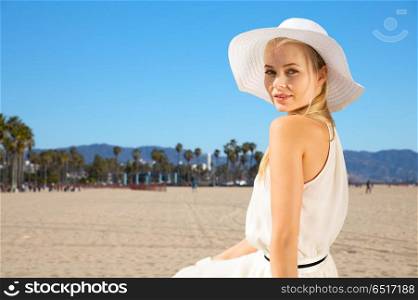 travel, tourism and summer vacation concept - beautiful woman in hat enjoying sun over venice beach background in california. beautiful woman enjoying summer over venice beach. beautiful woman enjoying summer over venice beach