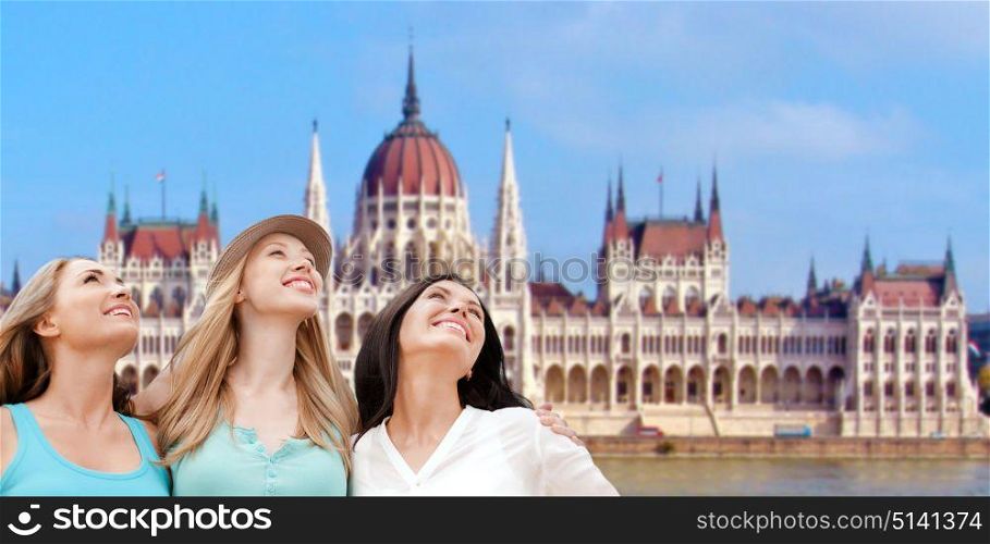 travel, tourism and summer vacation concept - group of happy smiling women or friends over house of parliament in budapest. happy women over house of parliament in budapest