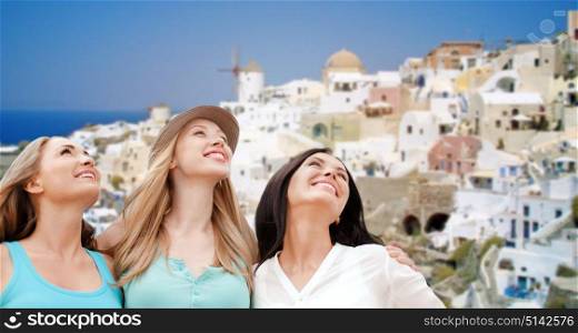 travel, tourism and summer vacation concept - group of happy smiling women or friends over oia town on santorini island background. happy women over santorini island background