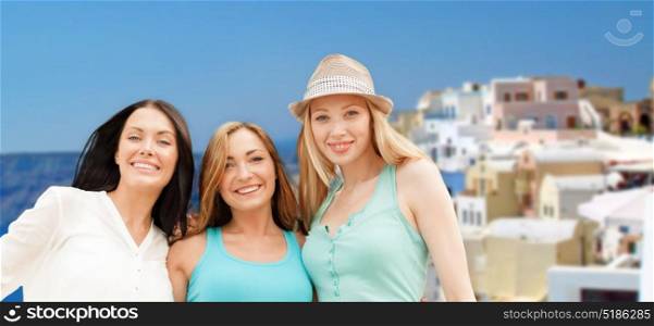 travel, tourism and summer vacation concept - group of happy smiling women or friends over santorini island background. happy women over santorini island background