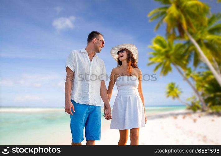 travel, tourism and summer vacation concept - happy couple on vacation wearing sunglasses and walking holding hands over tropical beach background in french polynesia. happy couple on vacation over tropical beach. happy couple on vacation over tropical beach