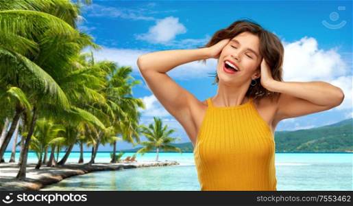 travel, tourism and summer vacation concept - happy laughing young woman in yellow top over tropical beach background in french polynesia. happy laughing young woman on tropical beach