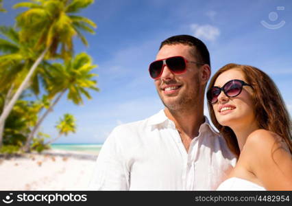 travel, tourism and summer vacation concept - happy smiling couple in sunglasses over tropical beach background in french polynesia. happy couple in sunglasses over tropical beach. happy couple in sunglasses over tropical beach