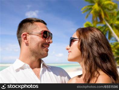travel, tourism and summer vacation concept - happy smiling couple in sunglasses over tropical beach background in french polynesia. happy couple in sunglasses over tropical beach. happy couple in sunglasses over tropical beach