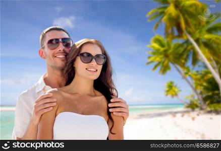 travel, tourism and summer vacation concept - happy smiling couple in sunglasses over tropical beach background in french polynesia. happy couple in sunglasses over tropical beach