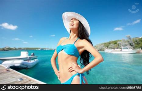 travel, tourism and summer vacation concept - happy smiling woman in bikini posing over wooden pier and boat on tropical beach background in french polynesia. happy smiling woman in bikini posing on beach
