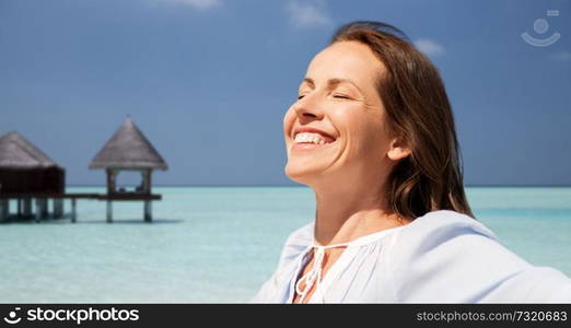 travel, tourism and summer vacation concept - happy smiling woman over exotic tropical beach and bungalow shed background. happy woman over beach and bungalow on background