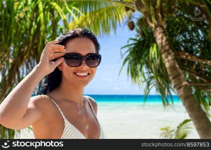 travel, tourism and summer vacation concept - happy smiling young woman in bikini swimsuit over tropical beach and palm trees background in french polynesia. smiling young woman in bikini swimsuit on beach