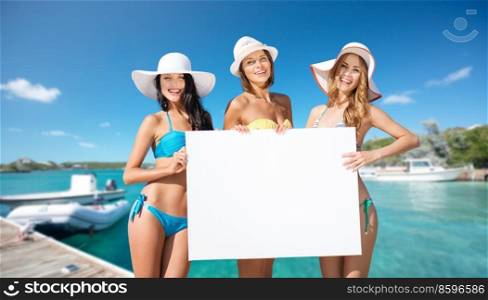 travel, tourism and summer vacation concept - happy women in bikinis holding blank white board over wooden pier and boat on tropical beach background in french polynesia. women in bikinis holding white board on beach