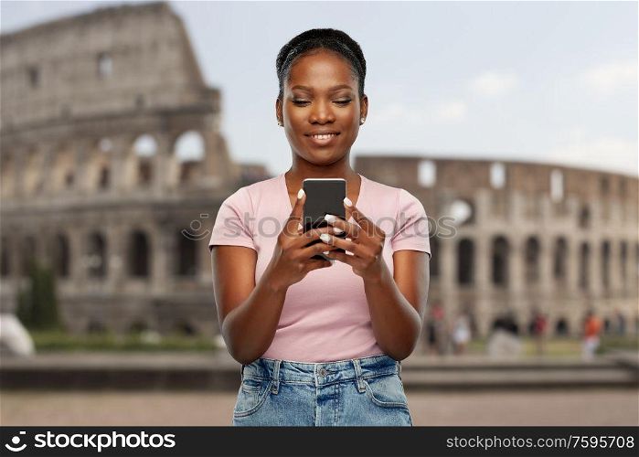 travel, tourism and technology c concept - happy african american woman using smartphone over coliseum background. african american woman with smartphone at coliseum