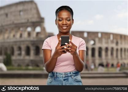 travel, tourism and technology c concept - happy african american woman using smartphone over coliseum background. african american woman with smartphone at coliseum
