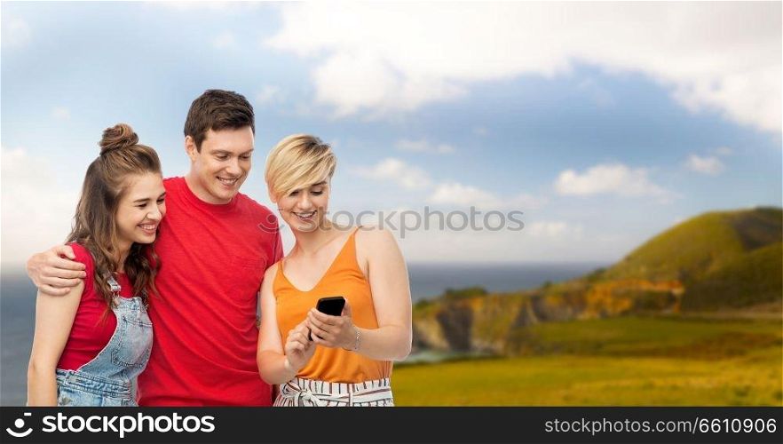 travel, tourism and technology concept - group of happy smiling friends with smartphone over big sur coast of california background. friends with smartphone over white background