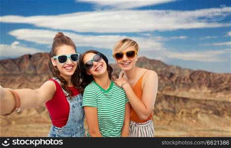 travel, tourism and vacation concept - group of happy female smiling friends in sunglasses taking selfie over grand canyon national park background. female friends taking selfie over grand canyon
