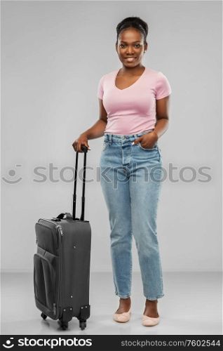 travel, tourism and vacation concept - happy african american young woman with carry-on bag over grey background. happy african american woman with travel bag