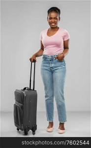 travel, tourism and vacation concept - happy african american young woman with carry-on bag over grey background. happy african american woman with travel bag