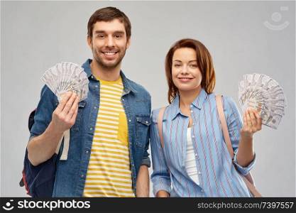 travel, tourism and vacation concept - happy couple of tourists with backpacks and money over grey background. couple of tourists with backpacks and money