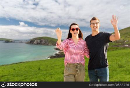 travel, tourism and vacation concept - happy couple waving hands over ireland on background. happy couple waving hands in ireland