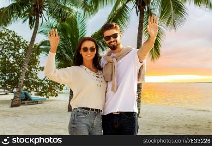 travel, tourism and vacation concept - happy couple waving hands over tropical beach background in french polynesia. happy couple waving hands on beach