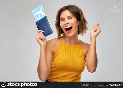 travel, tourism and vacation concept - happy laughing young woman in mustard yellow top with air ticket and passport over grey background. happy young woman with air ticket and passport