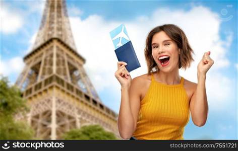travel, tourism and vacation concept - happy laughing young woman in yellow top with air ticket and passport over eiffel tower in paris, france background. happy woman with air ticket over eiffel tower