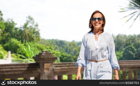 travel, tourism and vacation concept - happy smiling woman walking over terrace in thailand on background. happy smiling woman walking on terrace in thailand