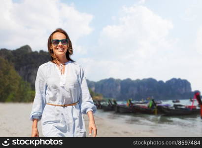 travel, tourism and vacation concept - happy smiling woman walking over tropical beach background in french polynesia. happy smiling woman walking along tropical beach